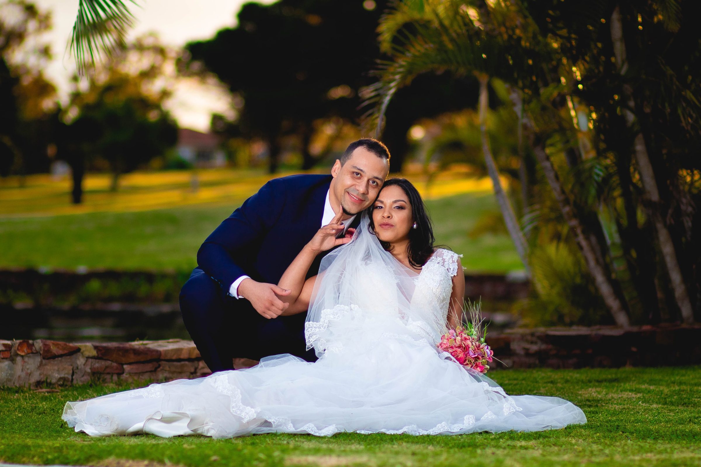Groom and Bride sitting down on grass at a park in Port Elizabeth called Victoria Park. Photographed by Adam Hendricks of Adam Hendricks Photography.