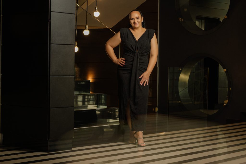 Woman dressed in black dress standing at the stairs, posing in the Hotel lobby for a photo